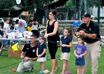 From left, Morgan City Police Sgt. Gary Keller, Ella Fryou, 4, Brandy Fryou, Hannah Fryou, 7, Emma Schaff, 4, and Morgan City Police Sgt. Mark Griffin Sr. practice casting fishing poles at Tuesday’s “Night Out Against Crime.”